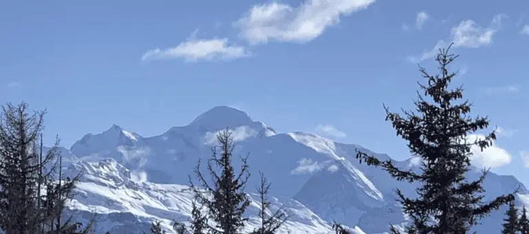 Verschneite Berglandschaft mit Tannen unter blauem Himmel